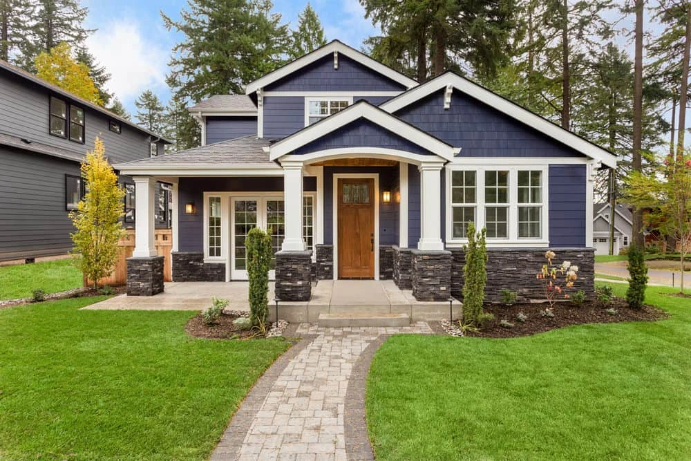 Blue craftsman-style house with stone column bases and a lawn