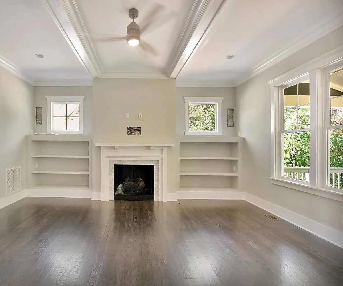 Empty living room with a fireplace and built-in shelves